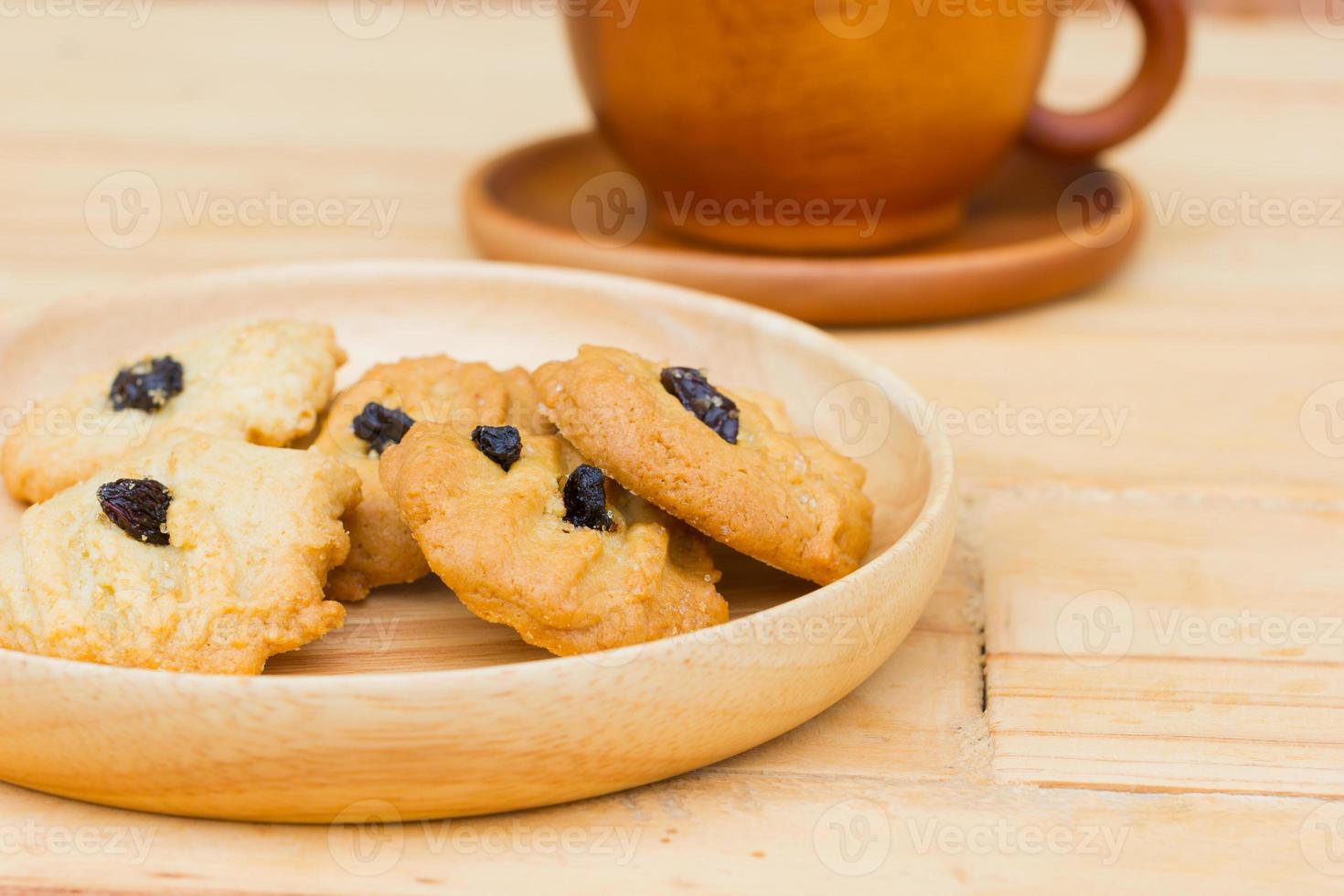 raisin cookies on wooden table with brown coffee cup photo