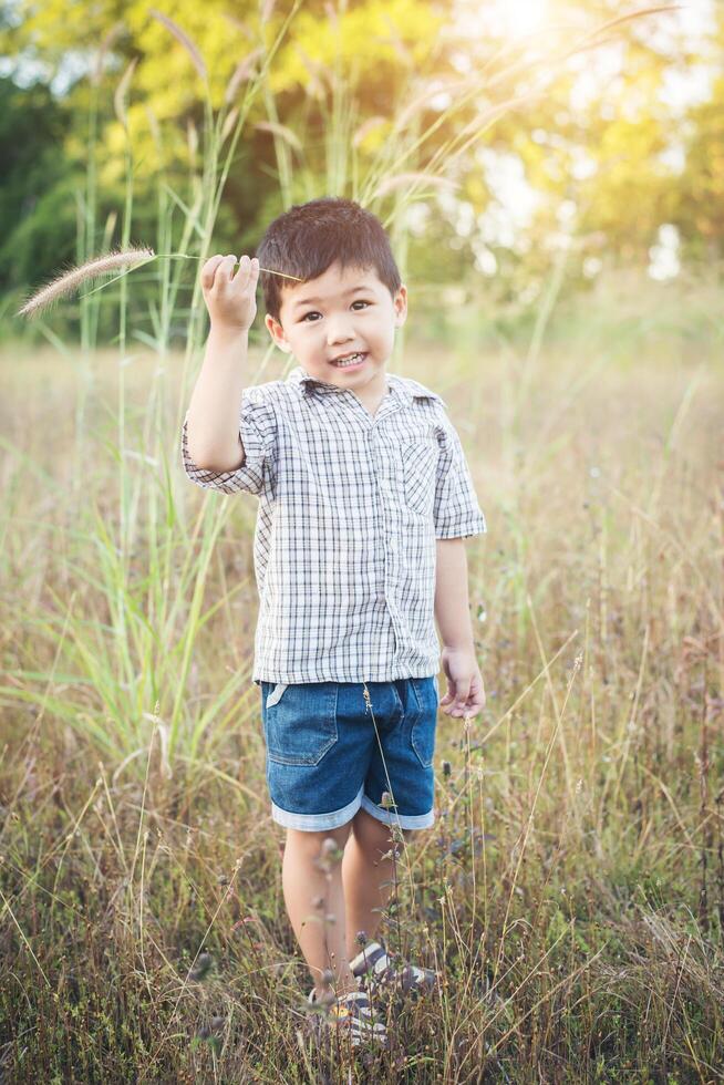 niño asiático feliz jugando al aire libre. lindo chico asiático en el campo. foto