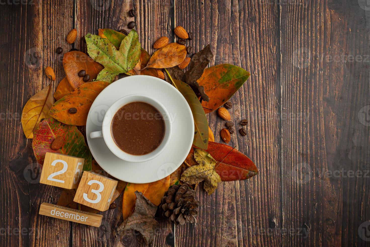 una taza de café tirada en el suelo y un calendario con hojas secas. foto