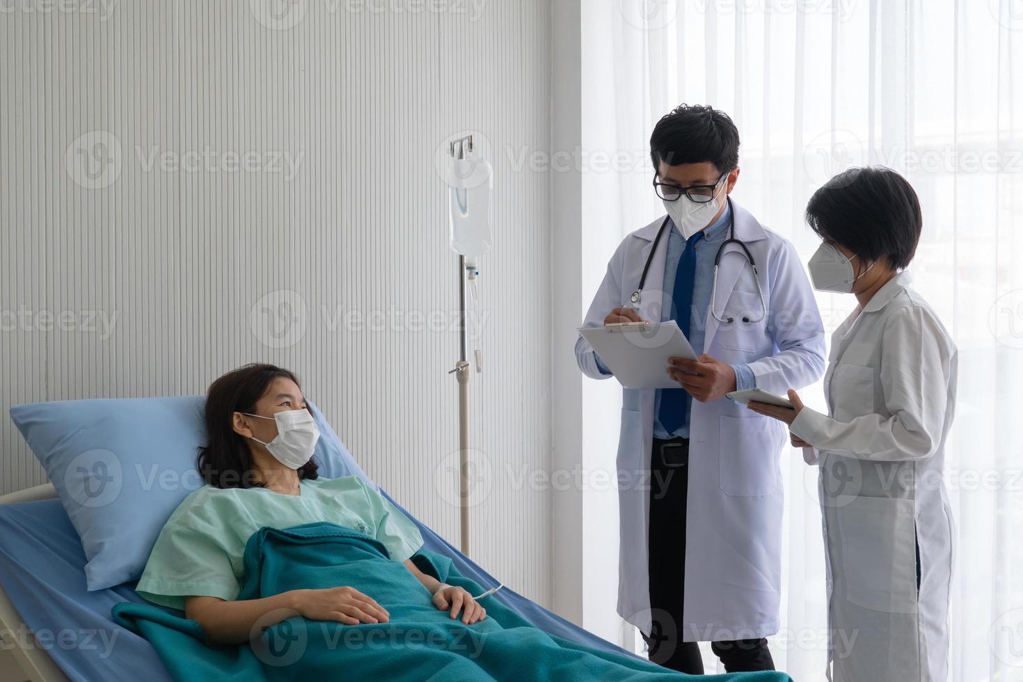 Médico y estudiante de medicina visitan al paciente en la sala del hospital. foto