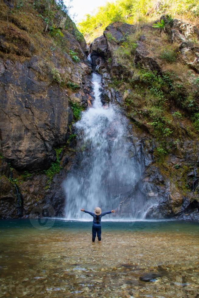 mujer de pie frente a la hermosa cascada. foto