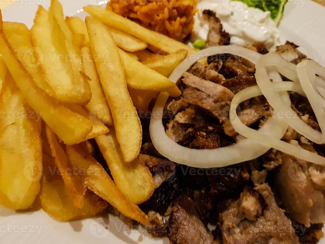 Gyros de comida griega con pommes frites y ensalada foto