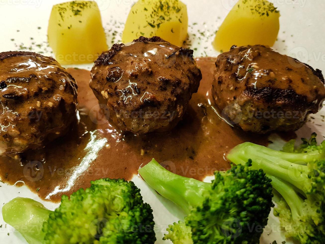 Fried meatballs with boiled broccoli and parsley potatoes photo