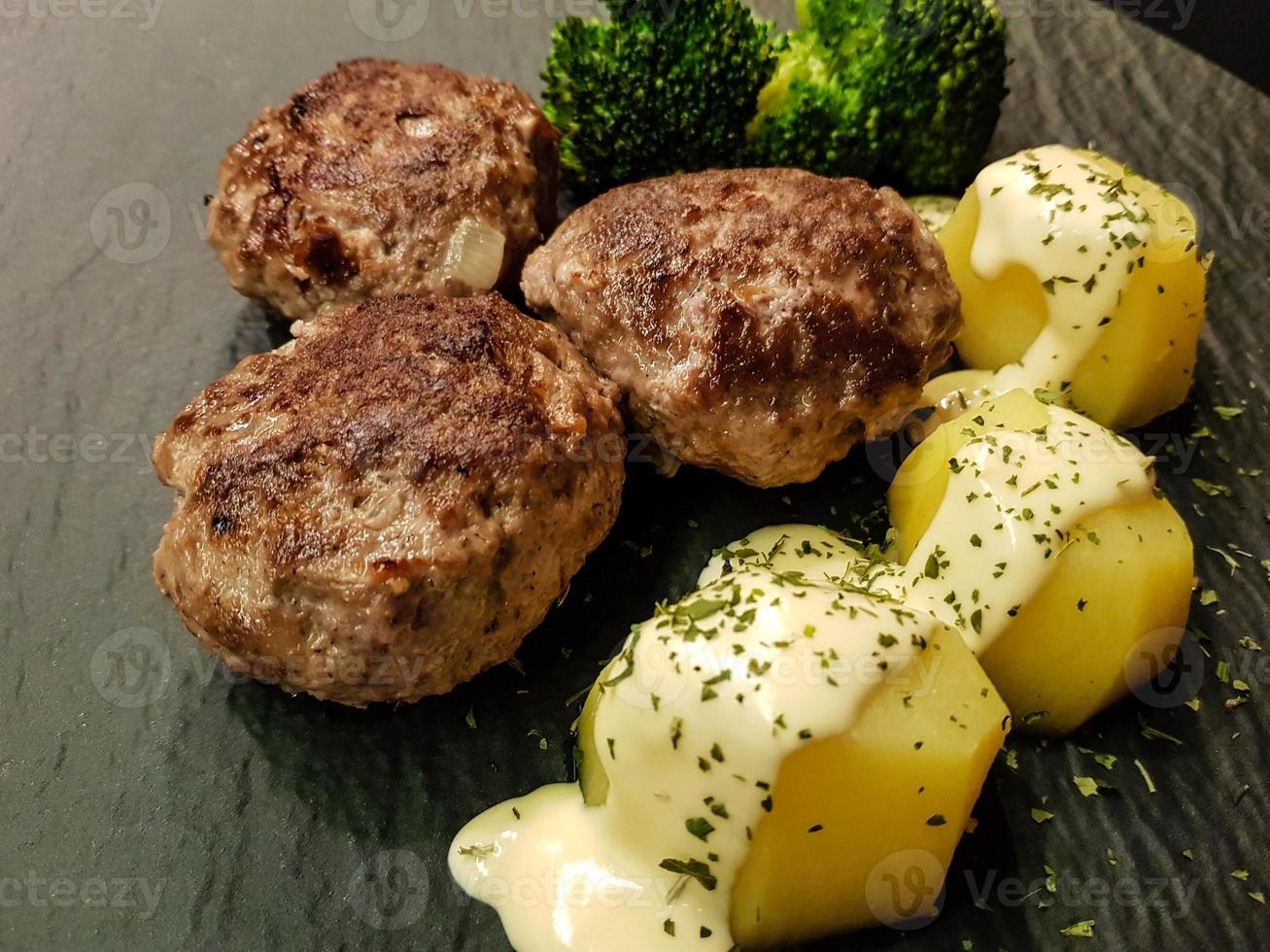 Fried meatballs with boiled broccoli and parsley potatoes photo