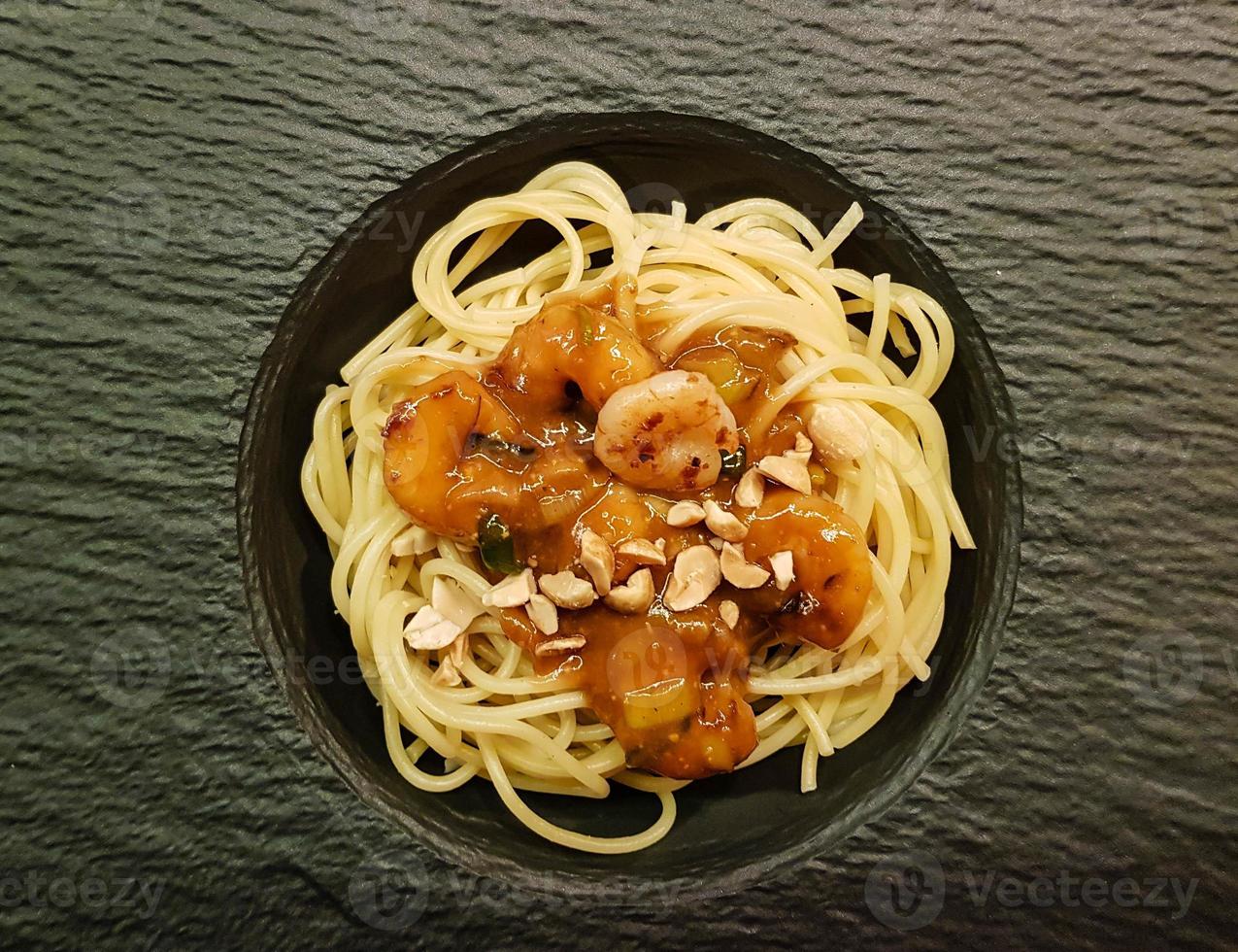 Langostinos tigre blancos en salsa de cacahuete sobre espaguetis foto