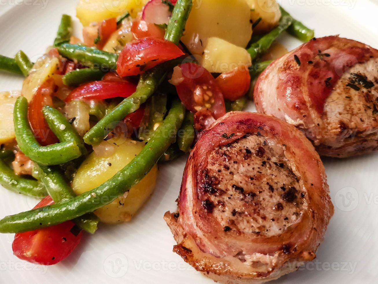 Pork tenderloin wrapped in bacon and salad photo