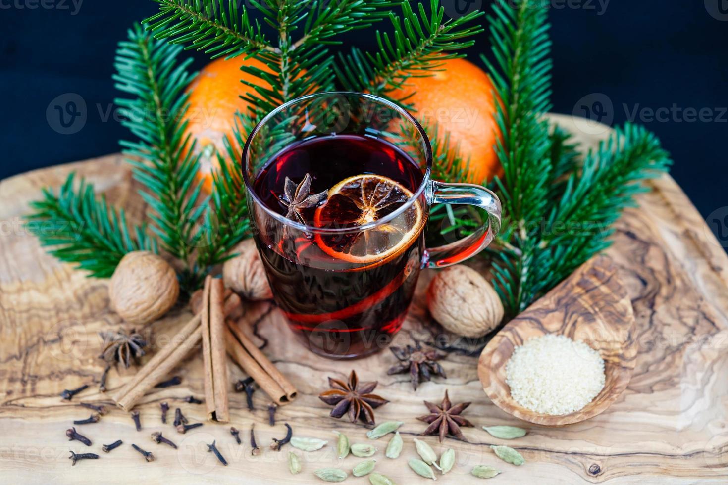 Vino caliente y especias navideñas sobre madera de olivo foto