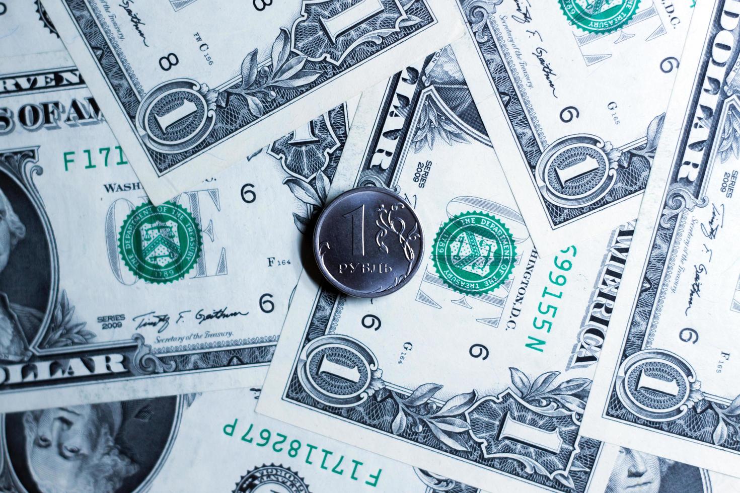 One ruble coin against the background of notes of american dollars. photo