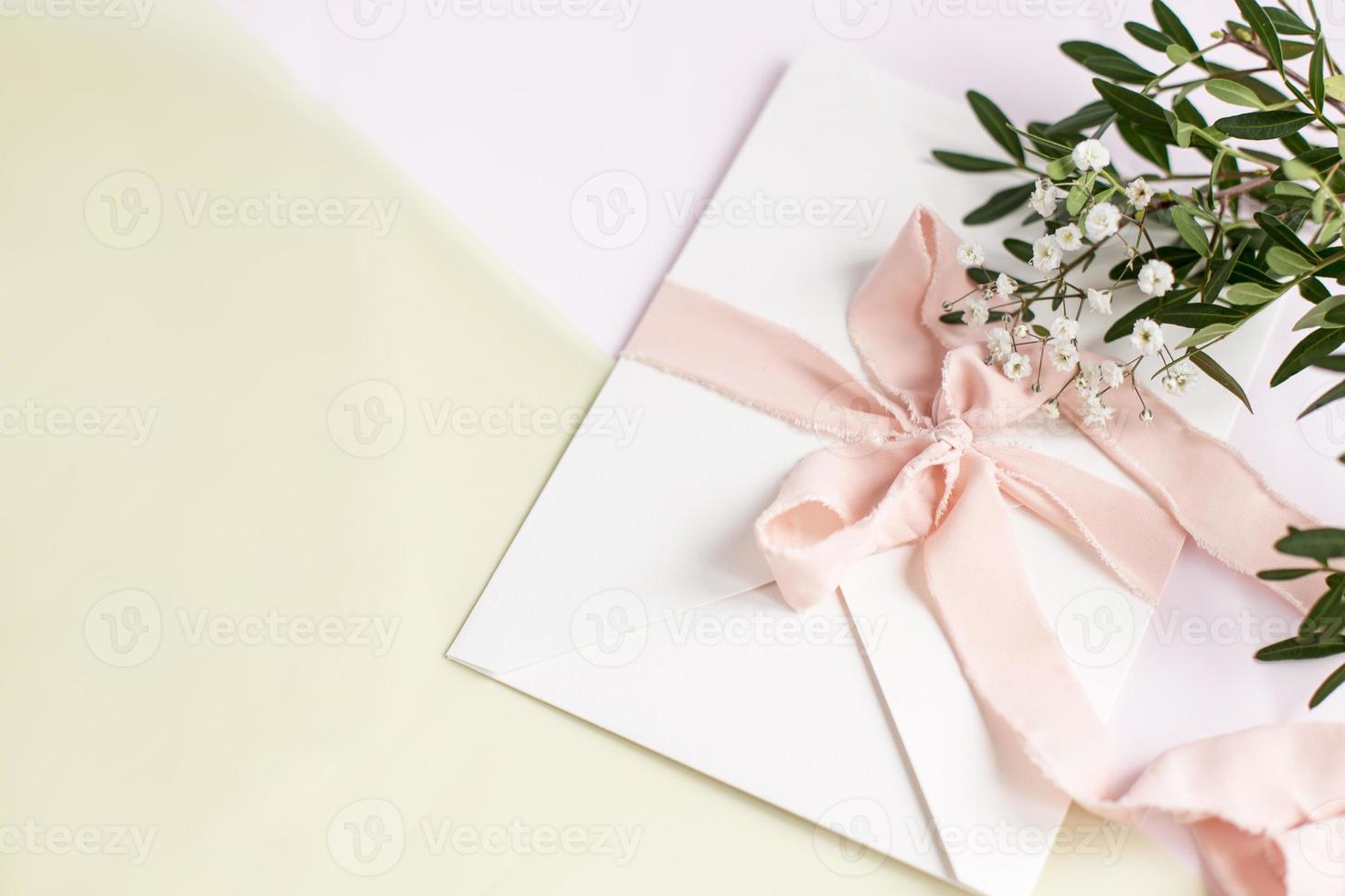 Envelope on a white-pink background with peach silk ribbon, flowers. photo