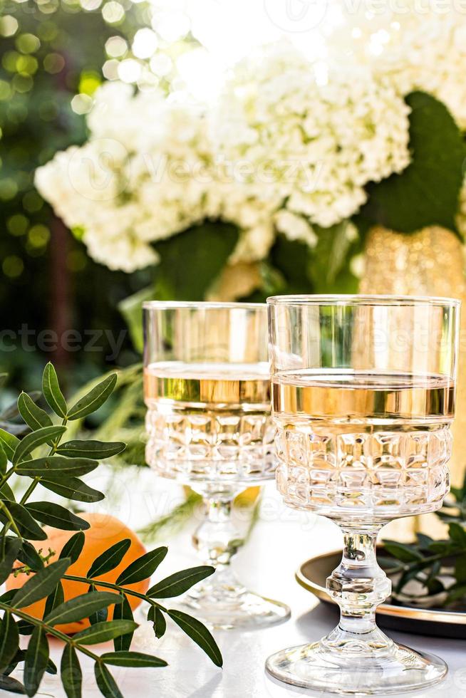 Rose wine in glasses on golden bottles with flowers and fruits photo