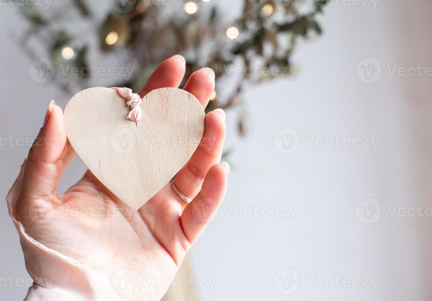 corazón de madera en cinta rosa. mano sosteniendo corazón de madera. copie el espacio. foto