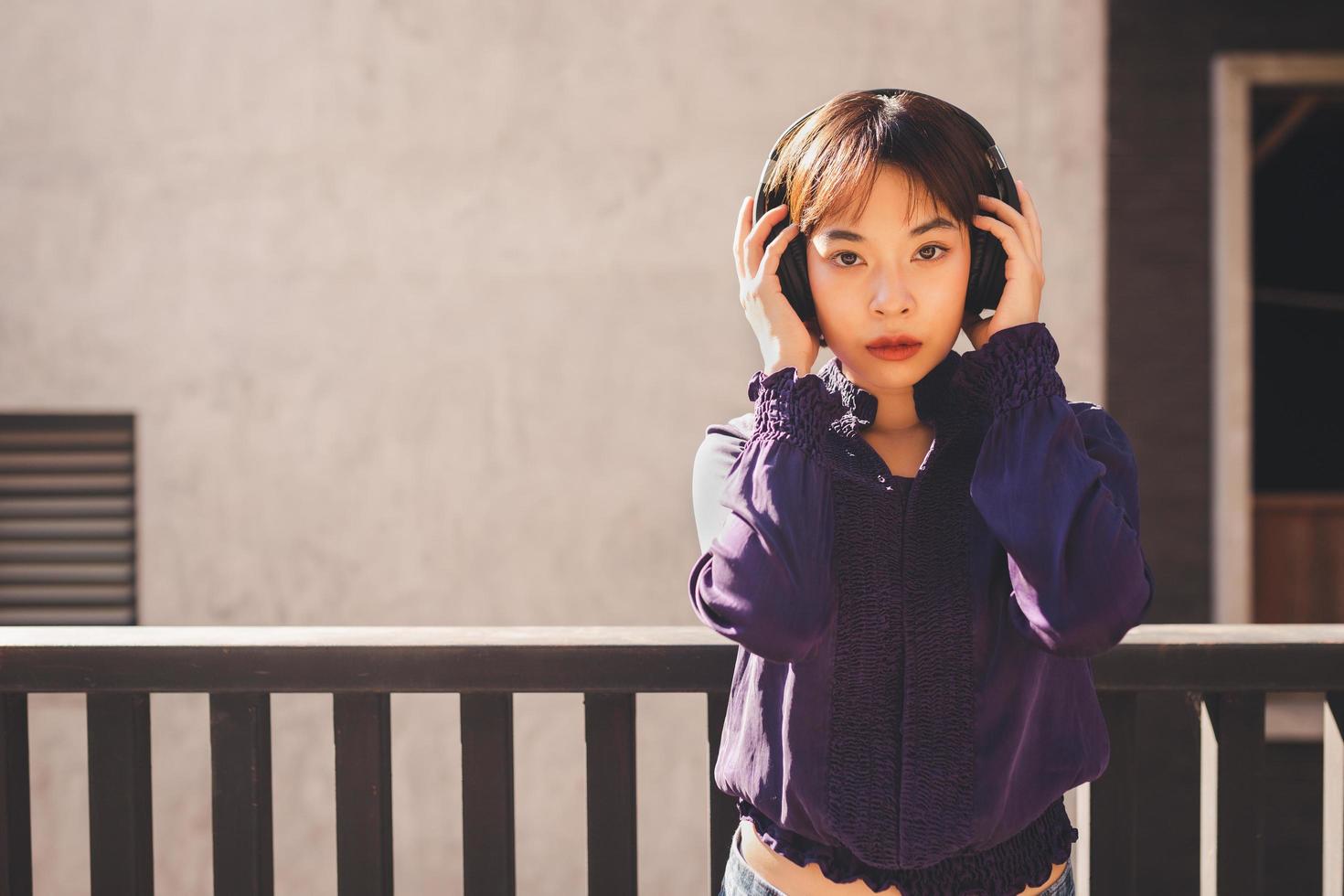 Feliz joven mujer asiática escuchando música con auriculares foto