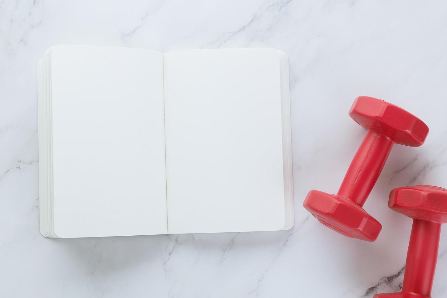 Blank notebook and dumbells on marble background photo