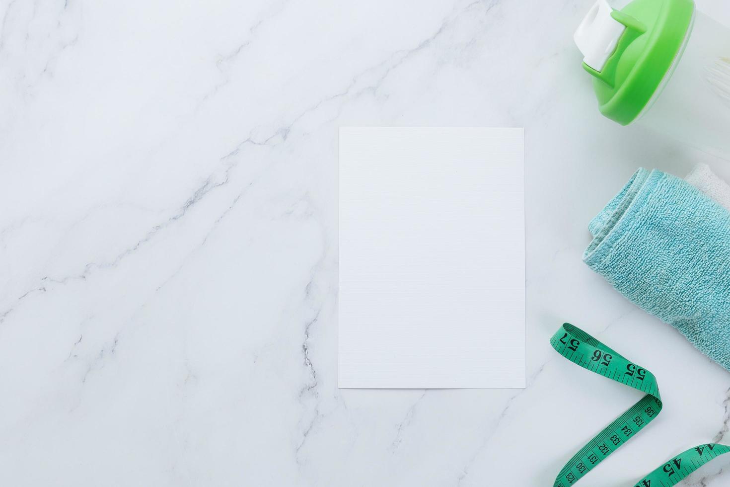 Blank white paper note and fitness equipment on marble background photo