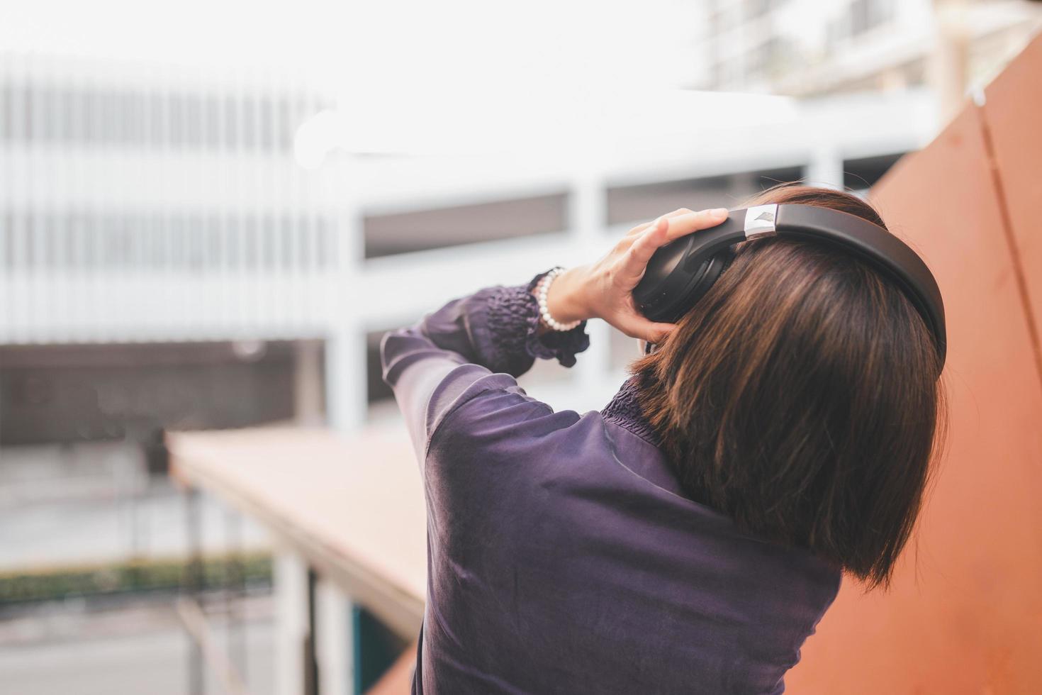 Feliz joven mujer asiática escuchando música con auriculares foto