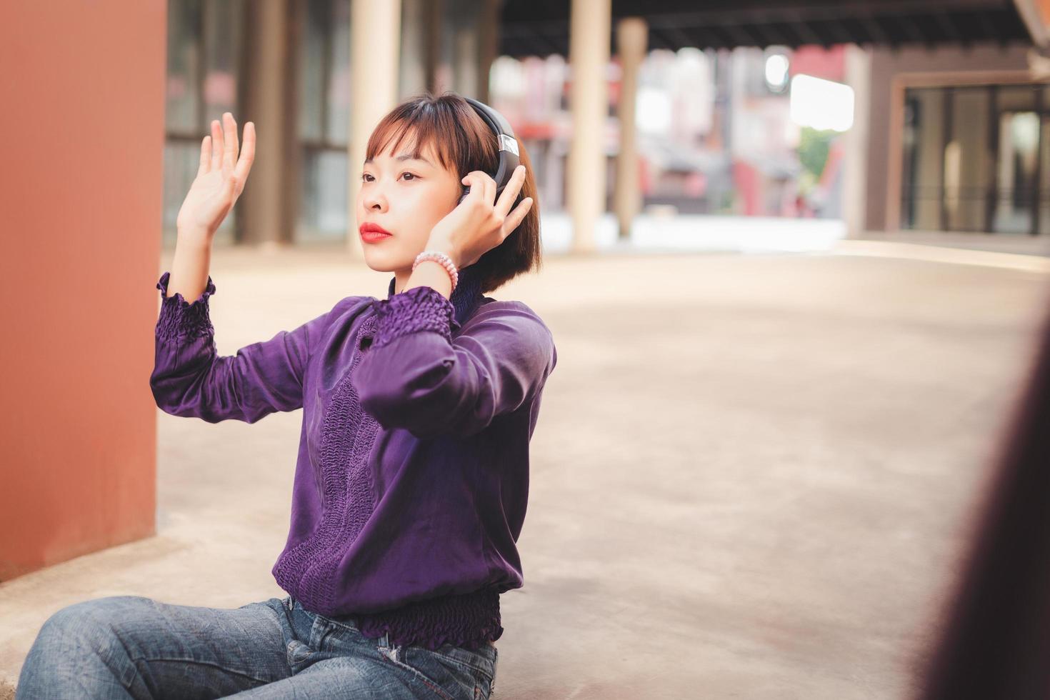 Feliz joven mujer asiática escuchando música con auriculares foto