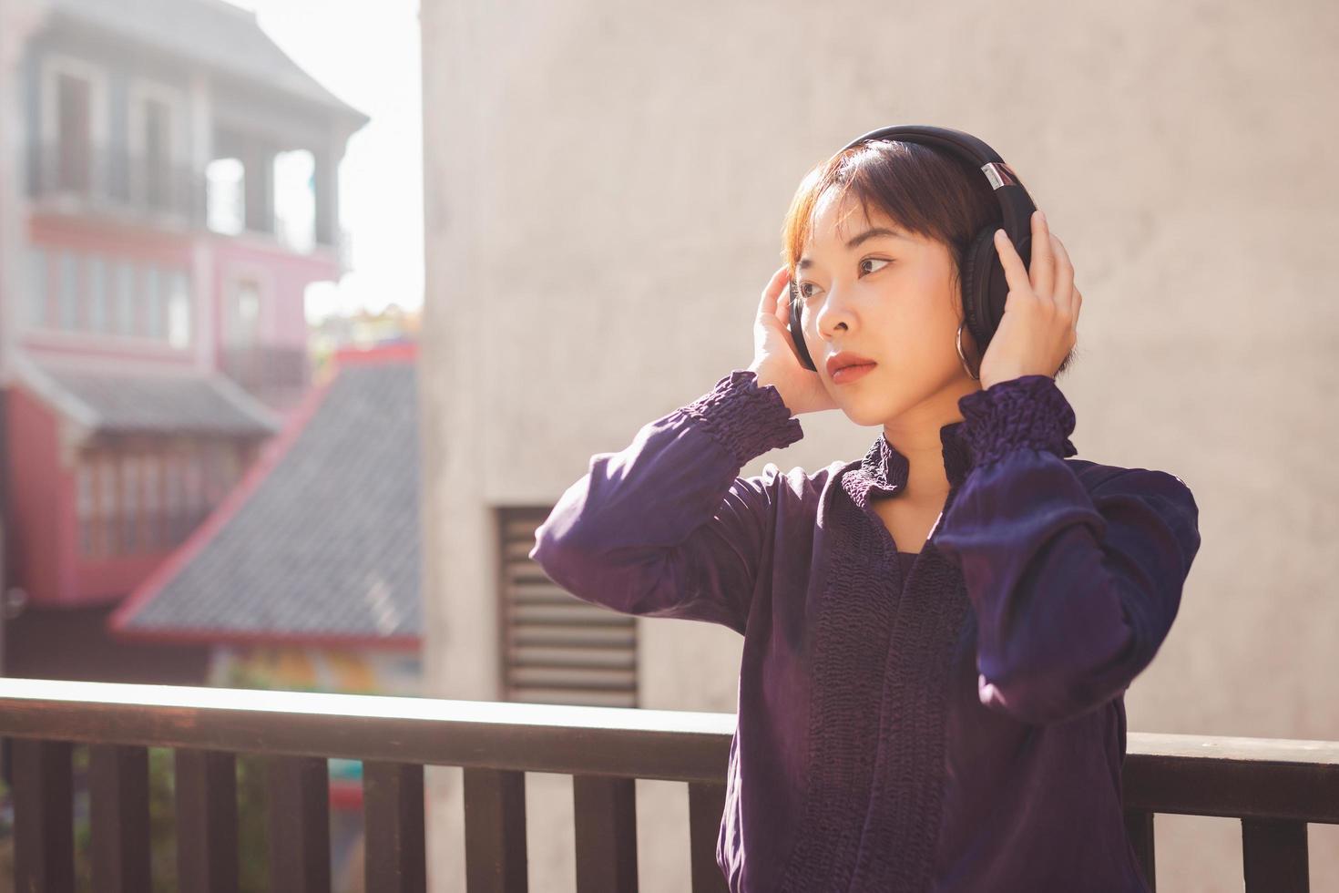 Happy young asian woman listening to music with headphones photo