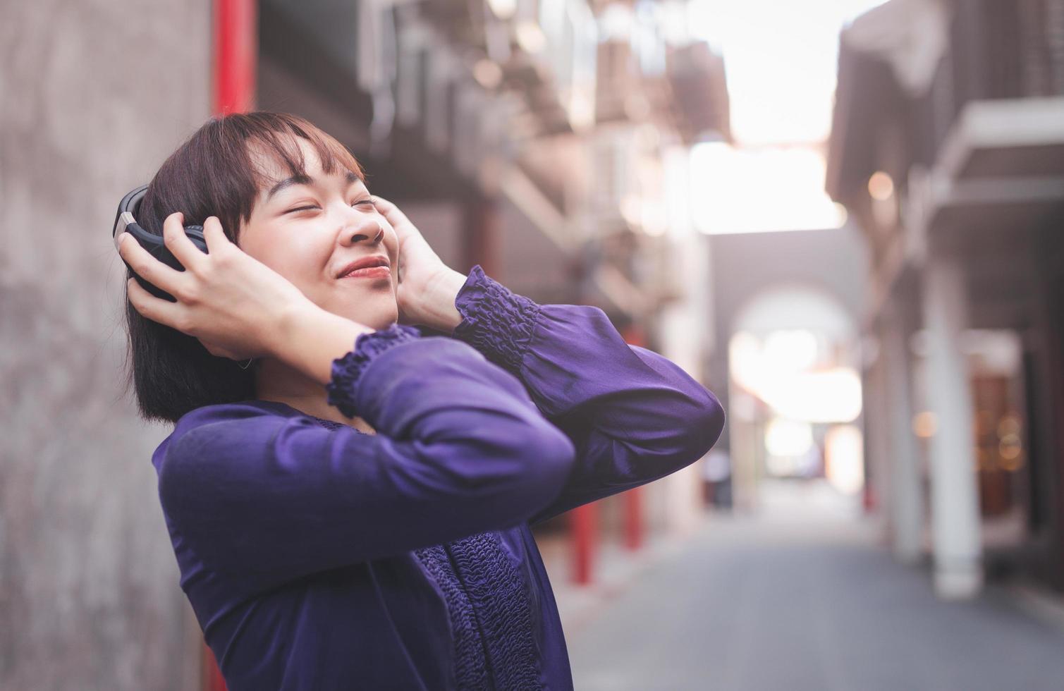 Feliz joven mujer asiática escuchando música con auriculares foto