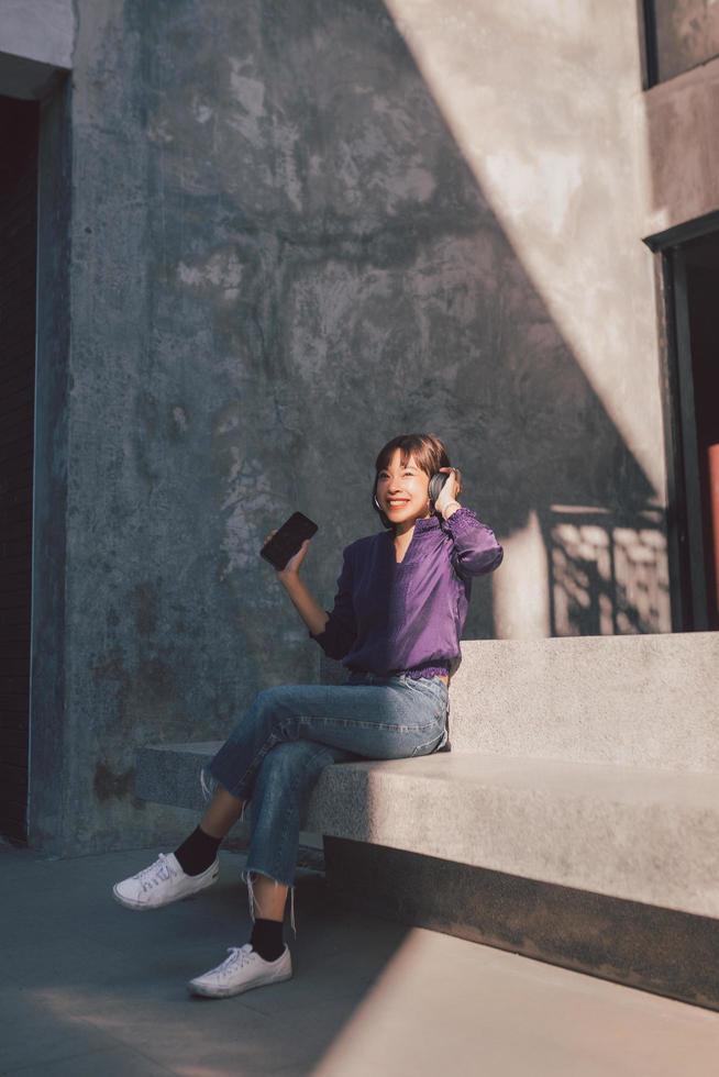 Feliz joven mujer asiática escuchando música con auriculares foto