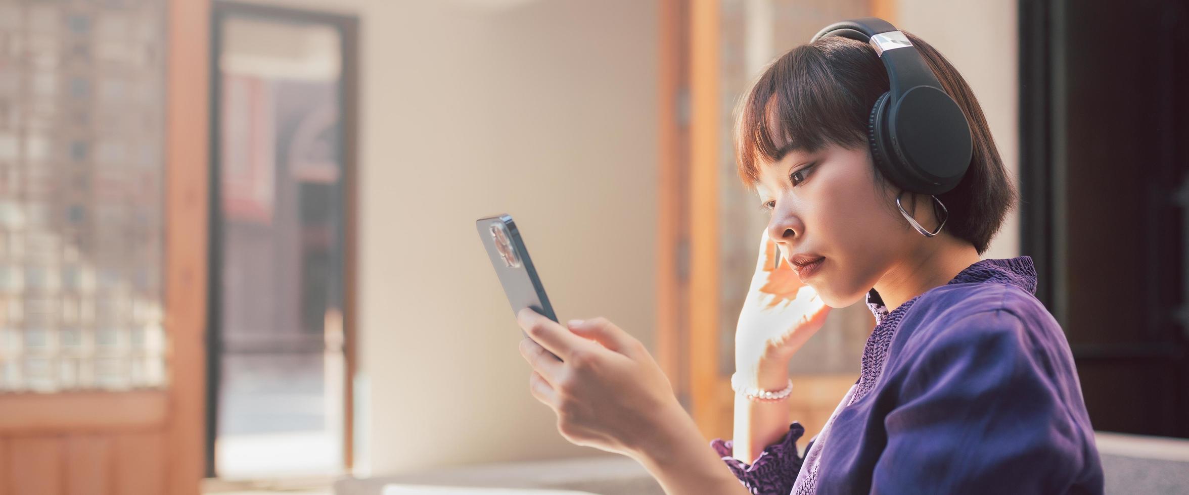 Feliz joven mujer asiática escuchando música con auriculares foto