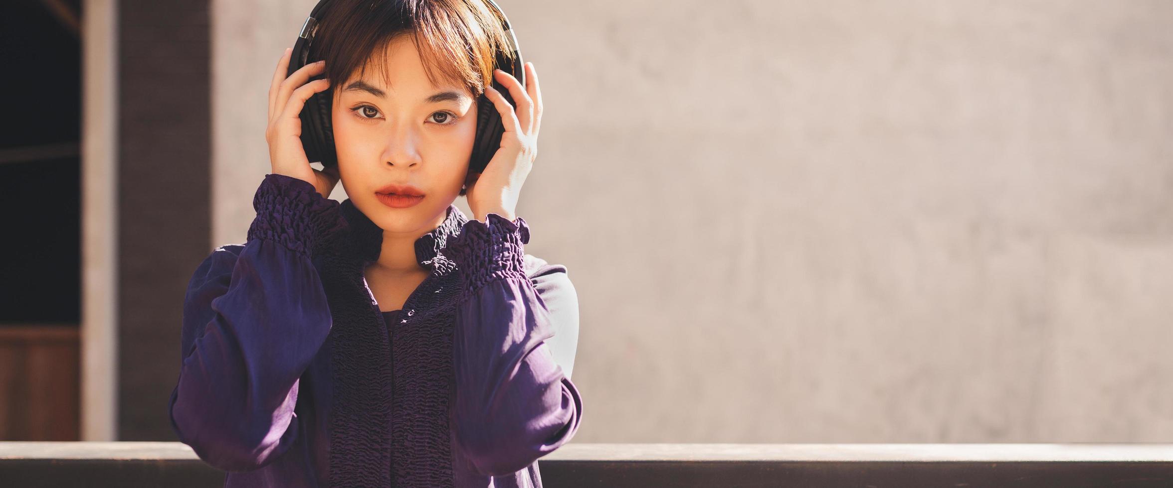 Feliz joven mujer asiática escuchando música con auriculares foto