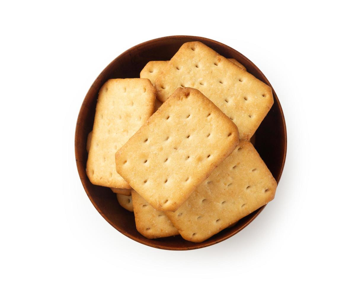 Galletas cracker en tazón de madera aislado sobre fondo blanco. foto