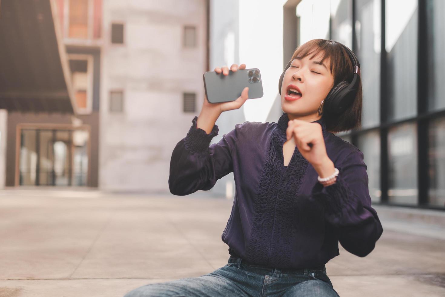 Feliz joven mujer asiática escuchando música con auriculares foto