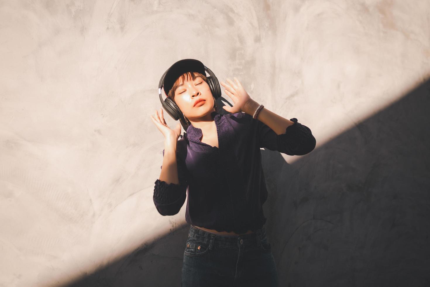 Feliz joven mujer asiática escuchando música con auriculares foto