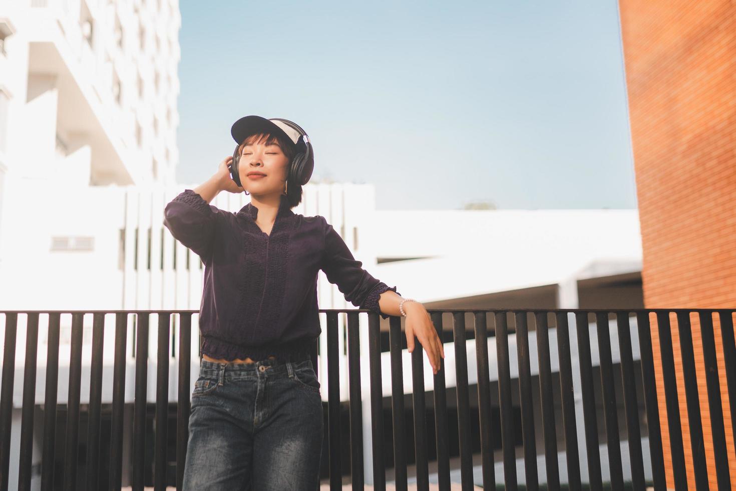 Feliz joven mujer asiática escuchando música con auriculares foto