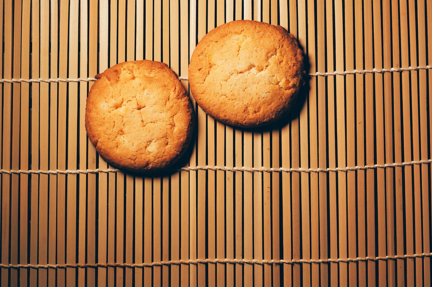 Two round crispy cookies, on textured bamboo, simple design photo