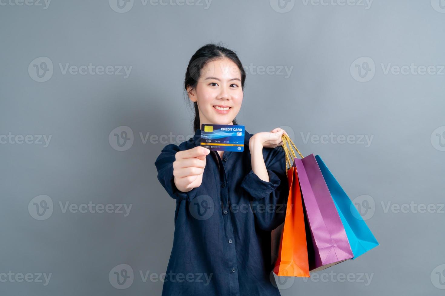 Hermosa mujer asiática con bolsas de la compra y mostrando tarjeta de crédito foto