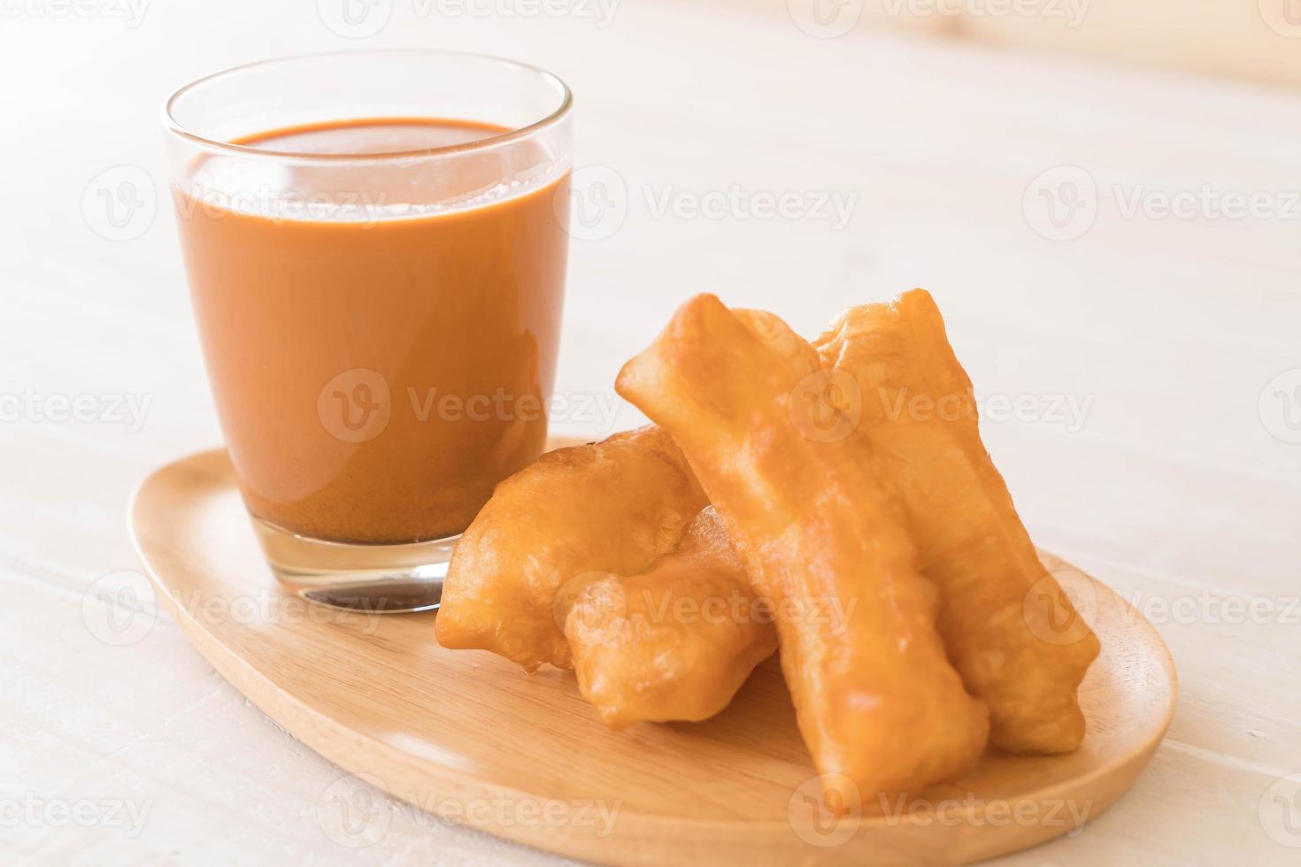 Palo de masa frita con té con leche sobre madera foto