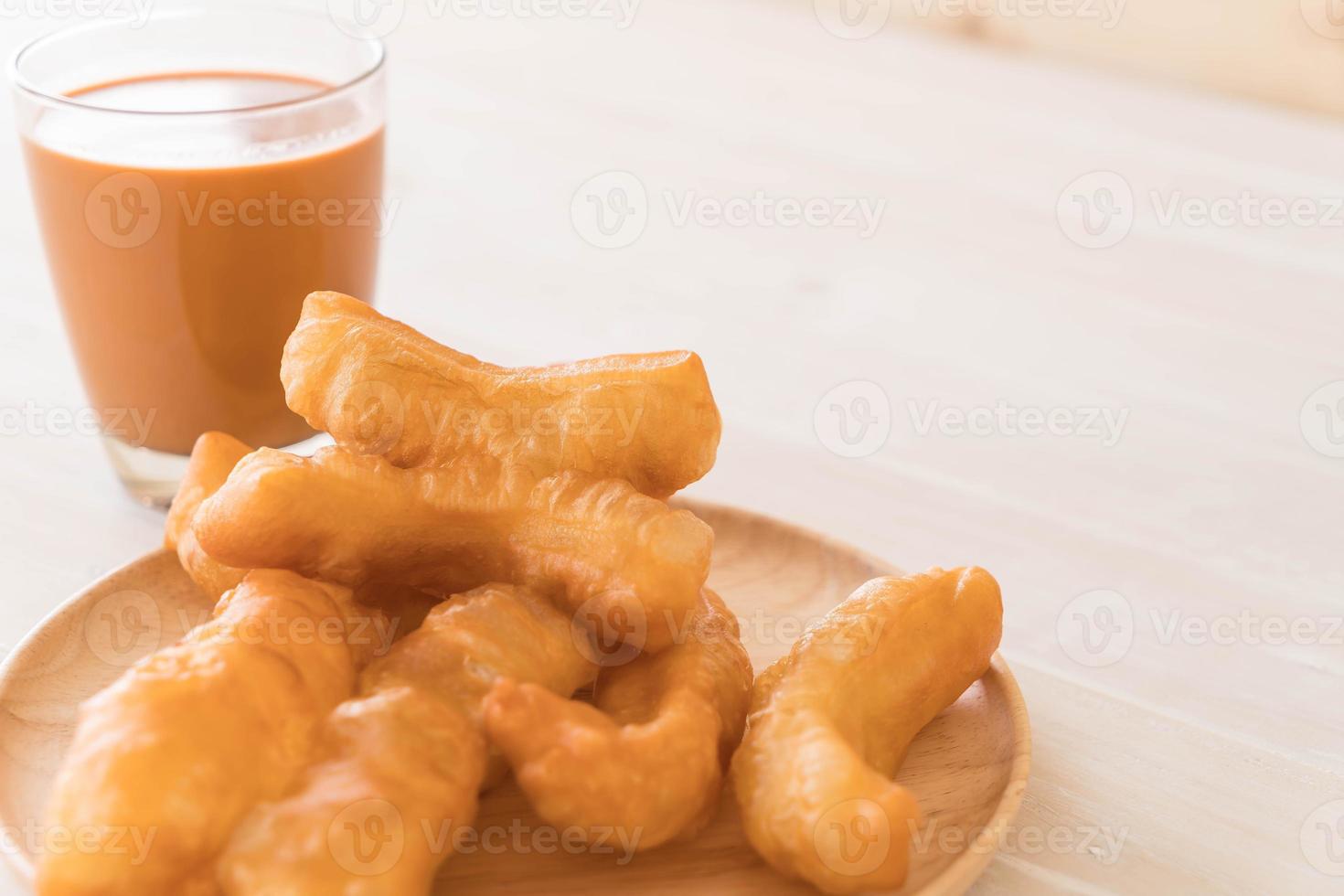 Palo de masa frita con té con leche sobre madera foto