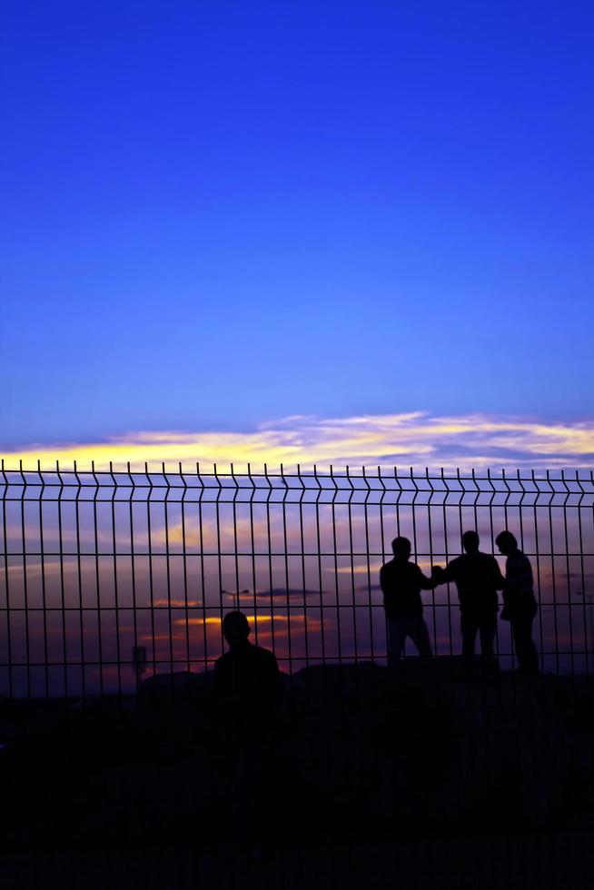 People Silhopuette Behind the Grate Fence photo