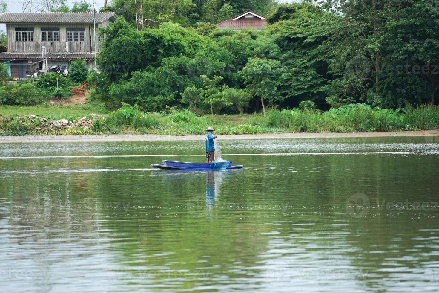 Lonely man stands on the boat and collects the fish from the net photo