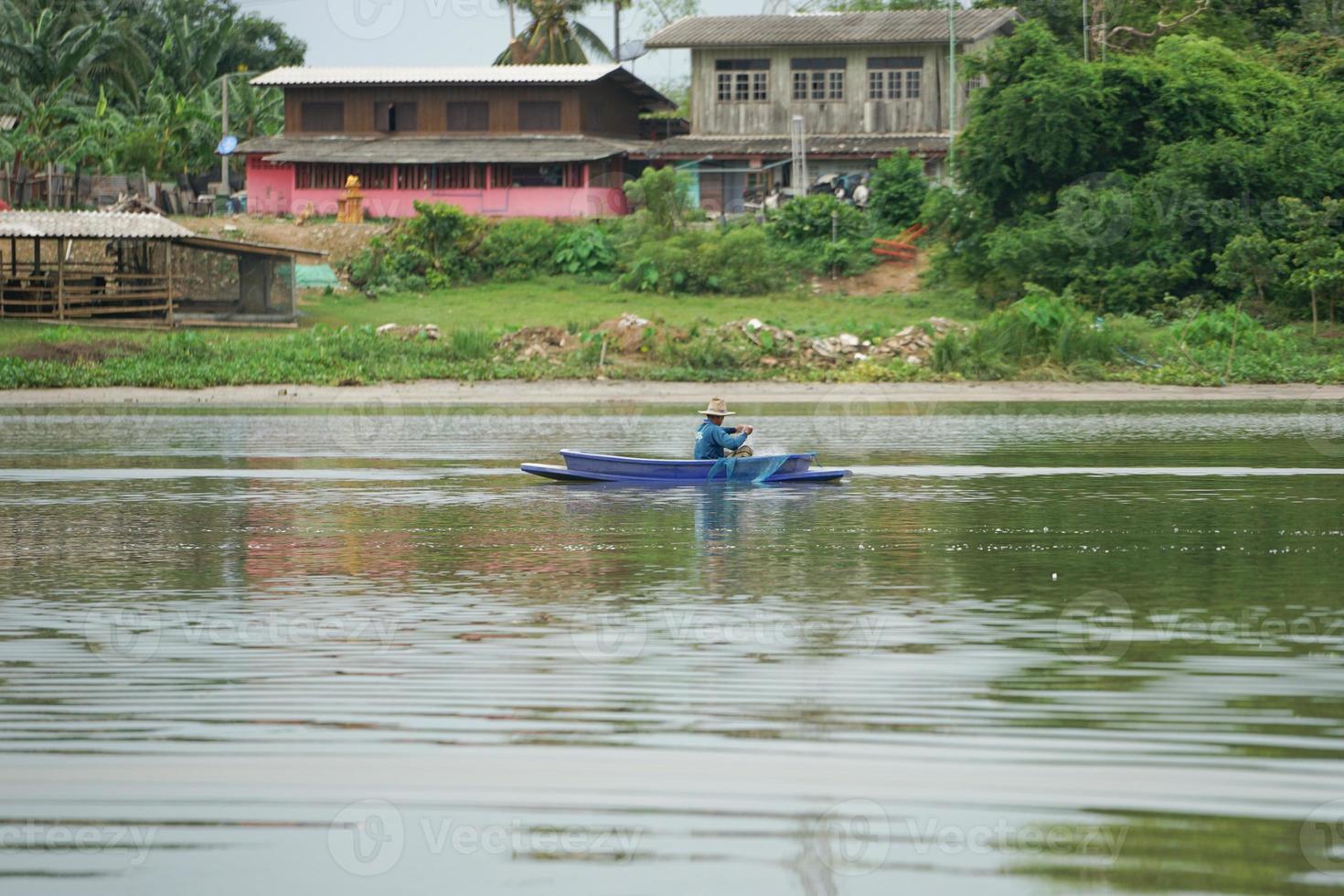 Lonely man sits in the boat and collects the fish from the net photo