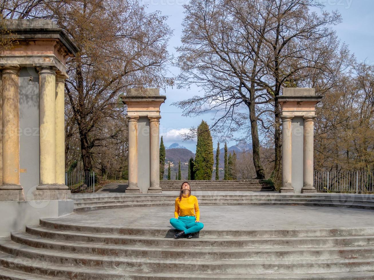 Smiling girl cross-legged on the staircase looking at the spring sun photo