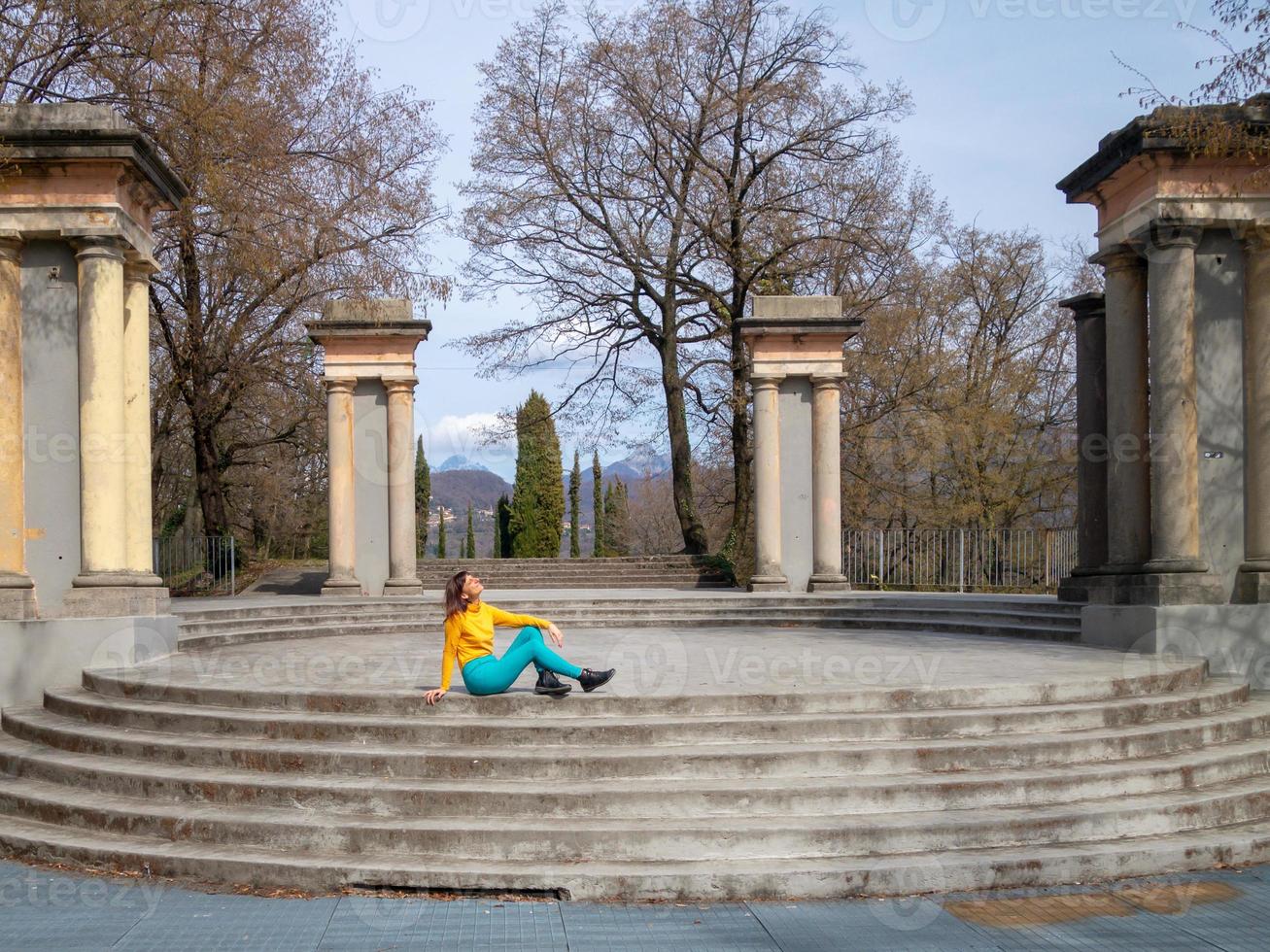 niña sonriente sentada en las escaleras del parque mirando el sol primaveral foto