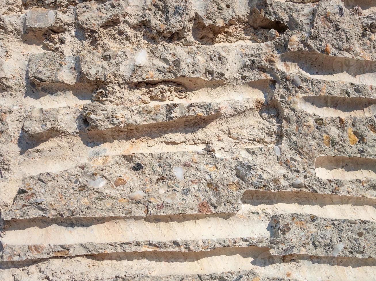 A wall made of small stones of various rocks and cement with sand photo