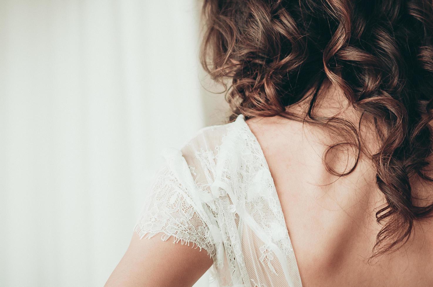 A brunette bride in white dress, a closeup view from the back photo