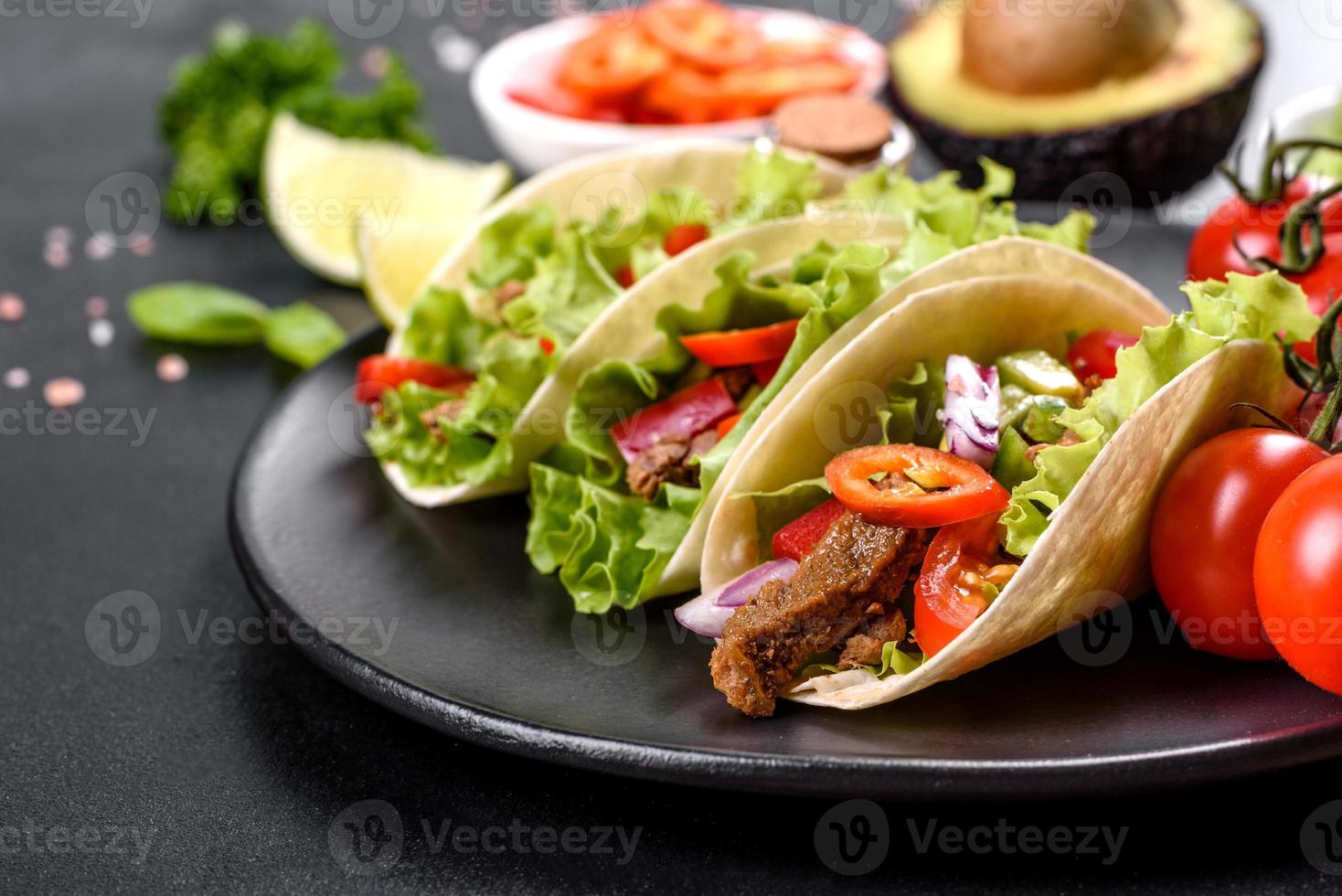 Mexican tacos with beef, tomatoes, avocado, onion and salsa sauce photo