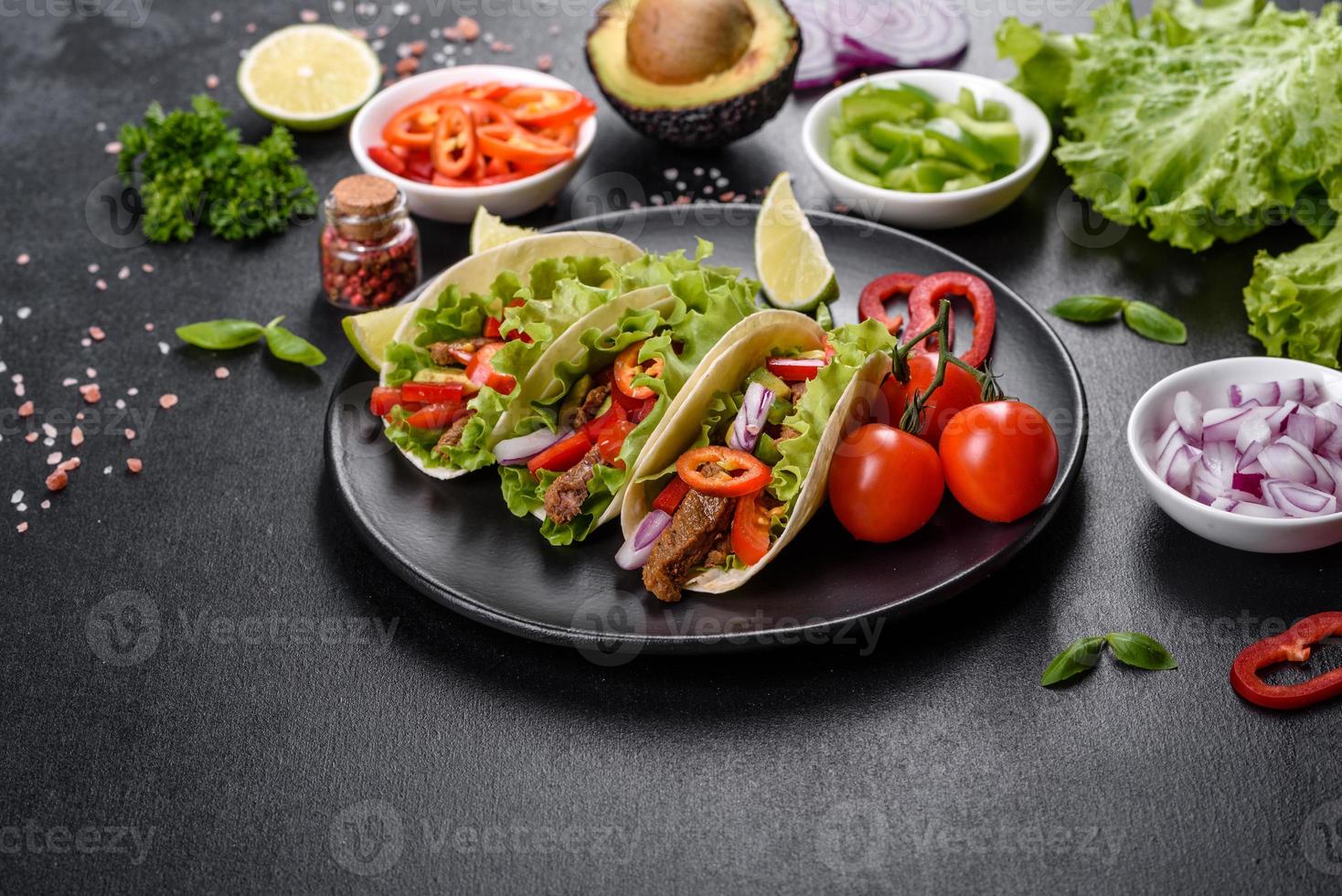 Mexican tacos with beef, tomatoes, avocado, onion and salsa sauce photo