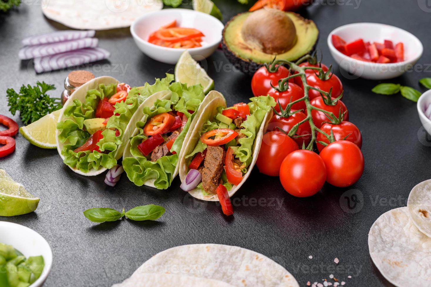 Mexican tacos with beef, tomatoes, avocado, onion and salsa sauce photo