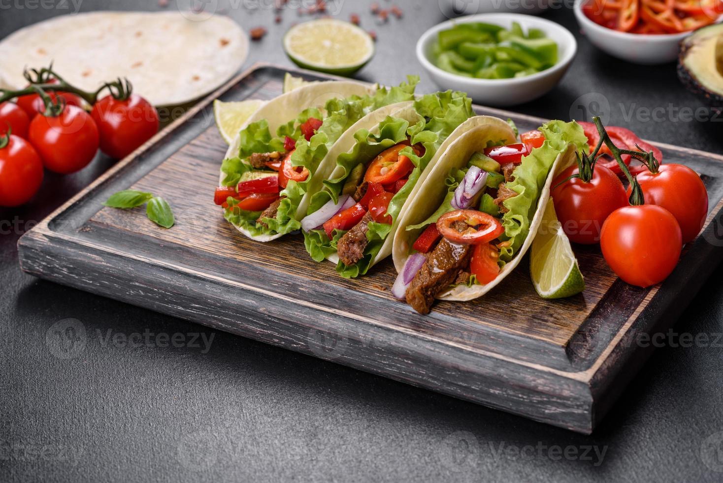 Mexican tacos with beef, tomatoes, avocado, onion and salsa sauce photo