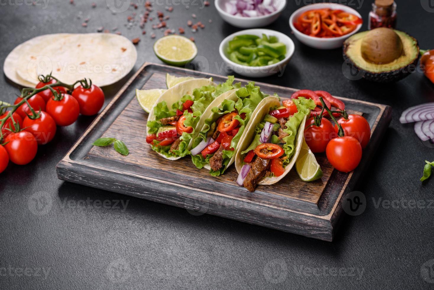 Mexican tacos with beef, tomatoes, avocado, onion and salsa sauce photo