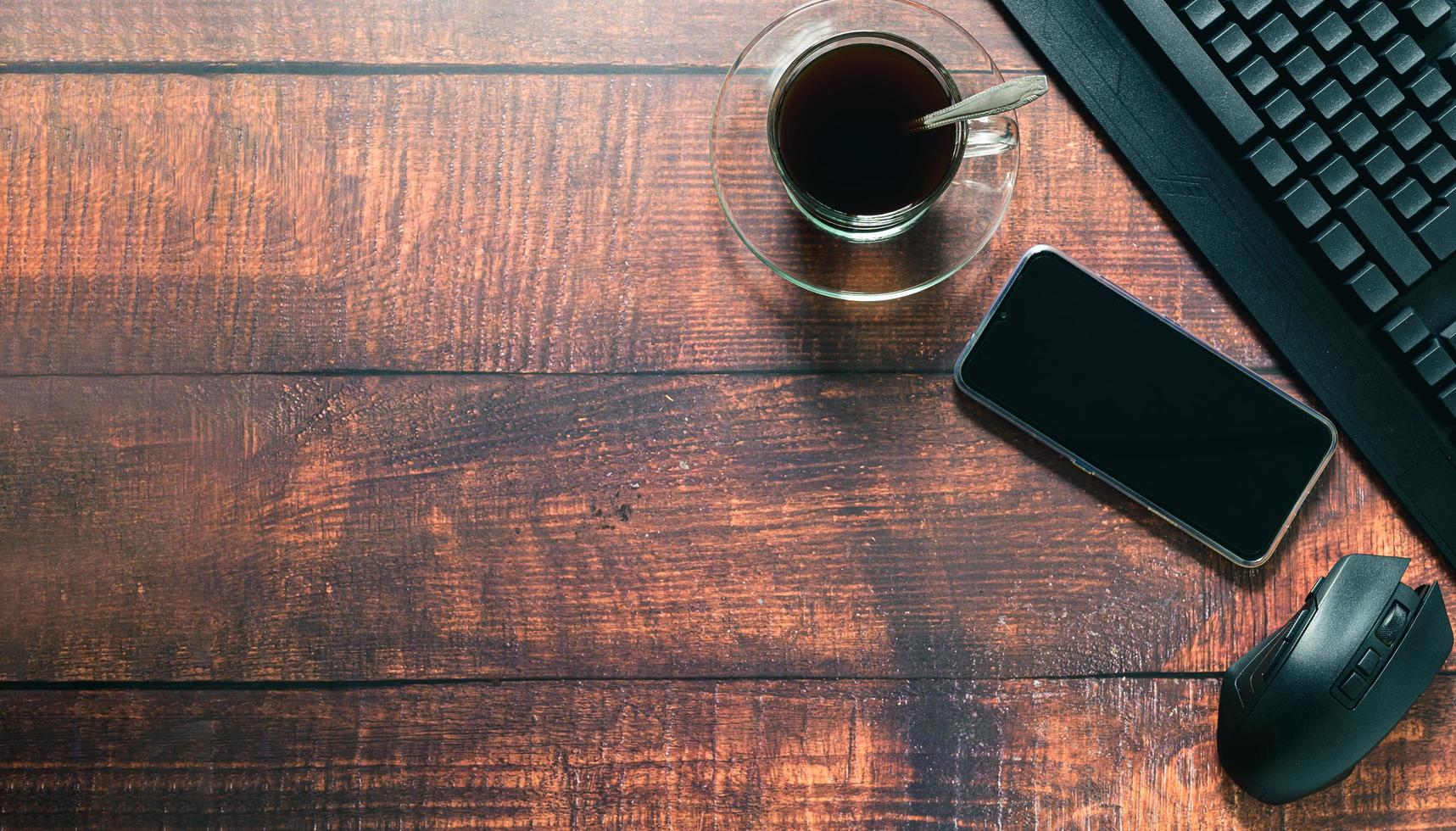 taza de café, teléfono inteligente, teclado, mouse en el escritorio. foto