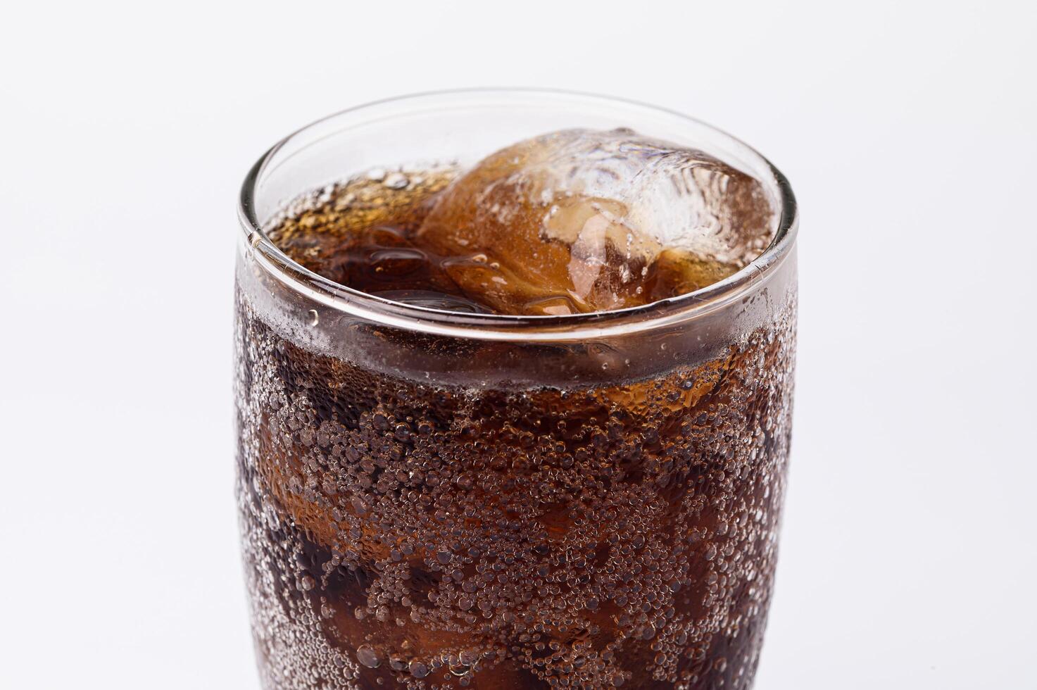 Cola en vaso con cubitos de hielo transparente aislado sobre fondo blanco. foto