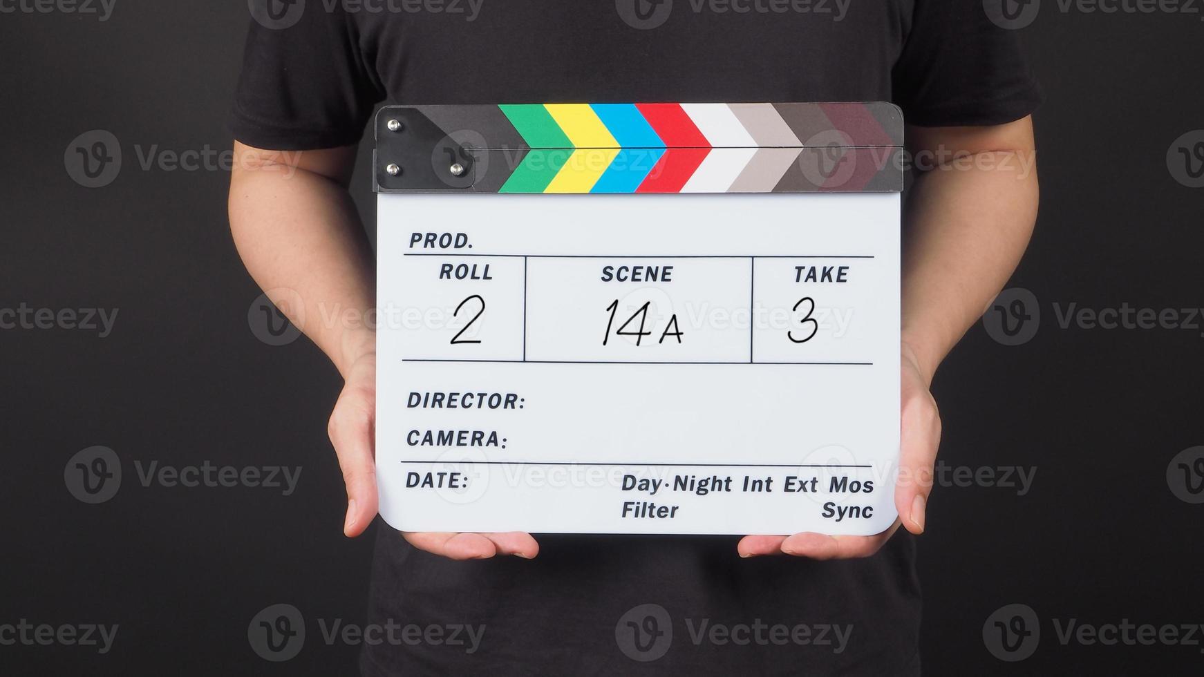 A man is hold Clapperboard with write in number on black background. photo
