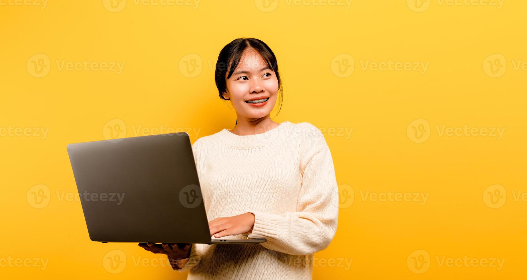 Concepto de comunicación en línea chica asiática usa portátil en casa amarillo foto