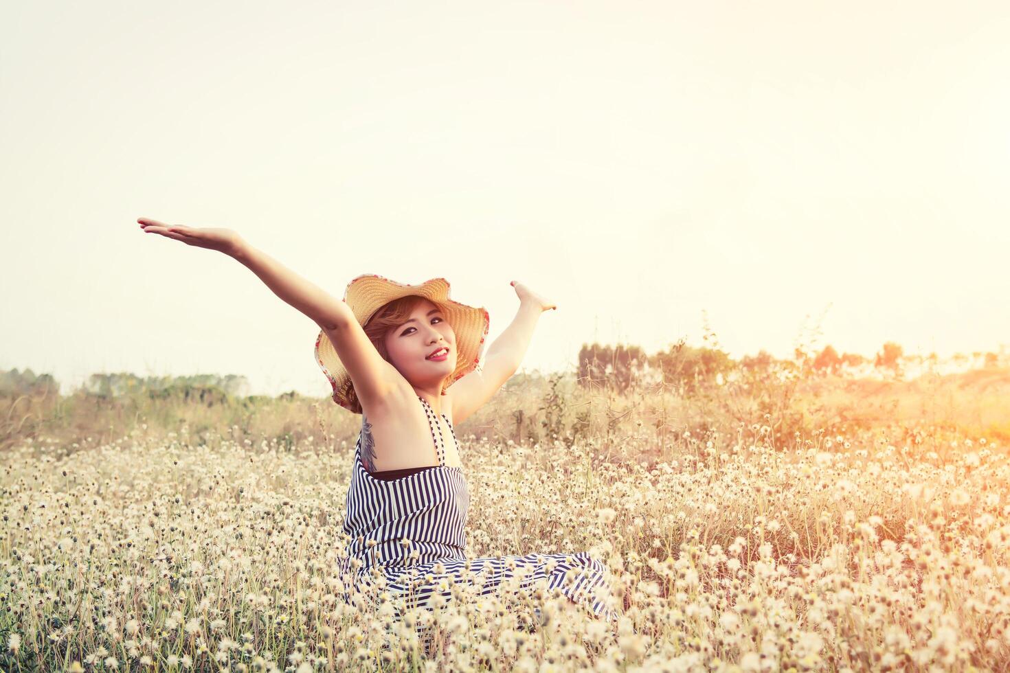 sexy hermosa mujer sentada en el campo de flores disfrutar y oler en flor foto